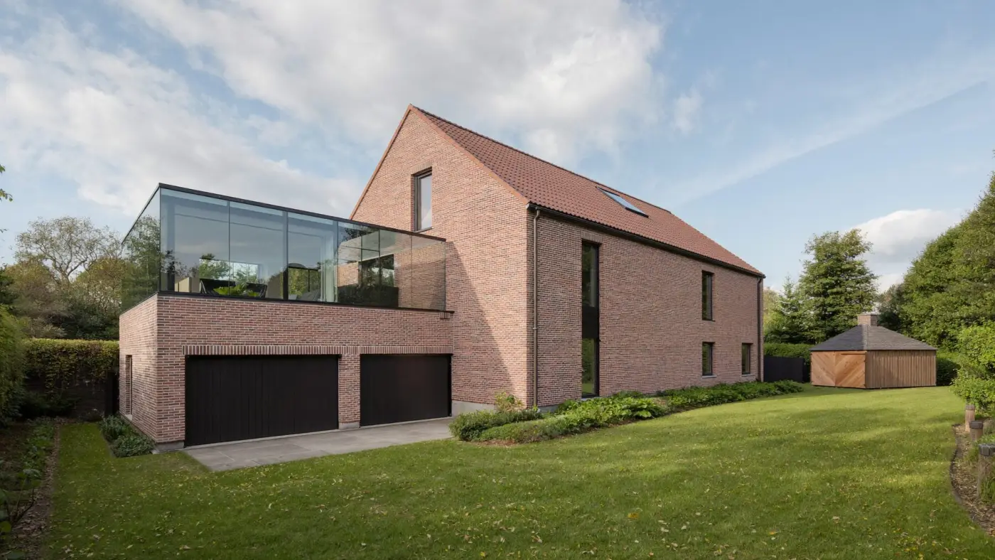 Maison en brique avec extension vitrée, double garage, abri de jardin et fenêtre de toit