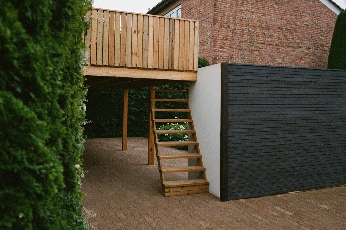 Terrasse surélevée en bois, allée pavée et clôture en bordure de propriété