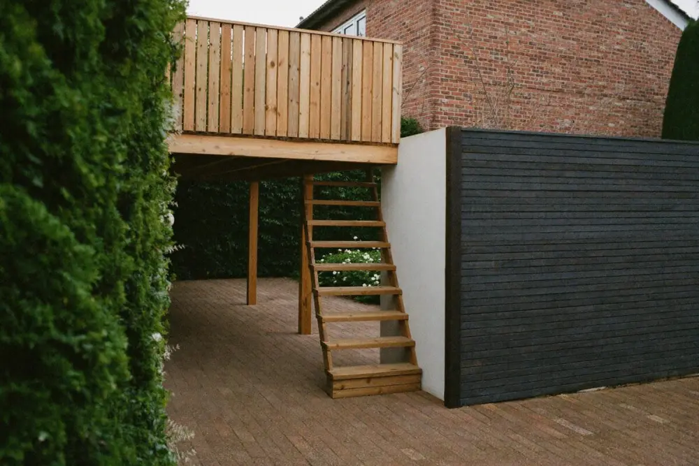 Terrasse surélevée en bois, allée pavée et clôture en bordure de propriété